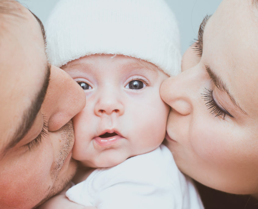 Ein Mann und eine Frau küssen ein Baby